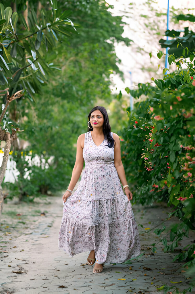 Young woman wearing a boho-chic floral maxi dress walking gracefully through a garden path.